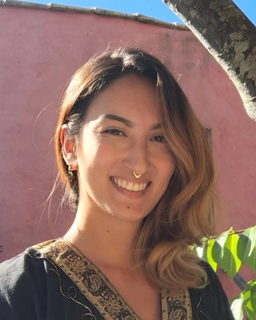 Gabrielle Guerretta sorrindo, diante de um muro rosa em dia de sol